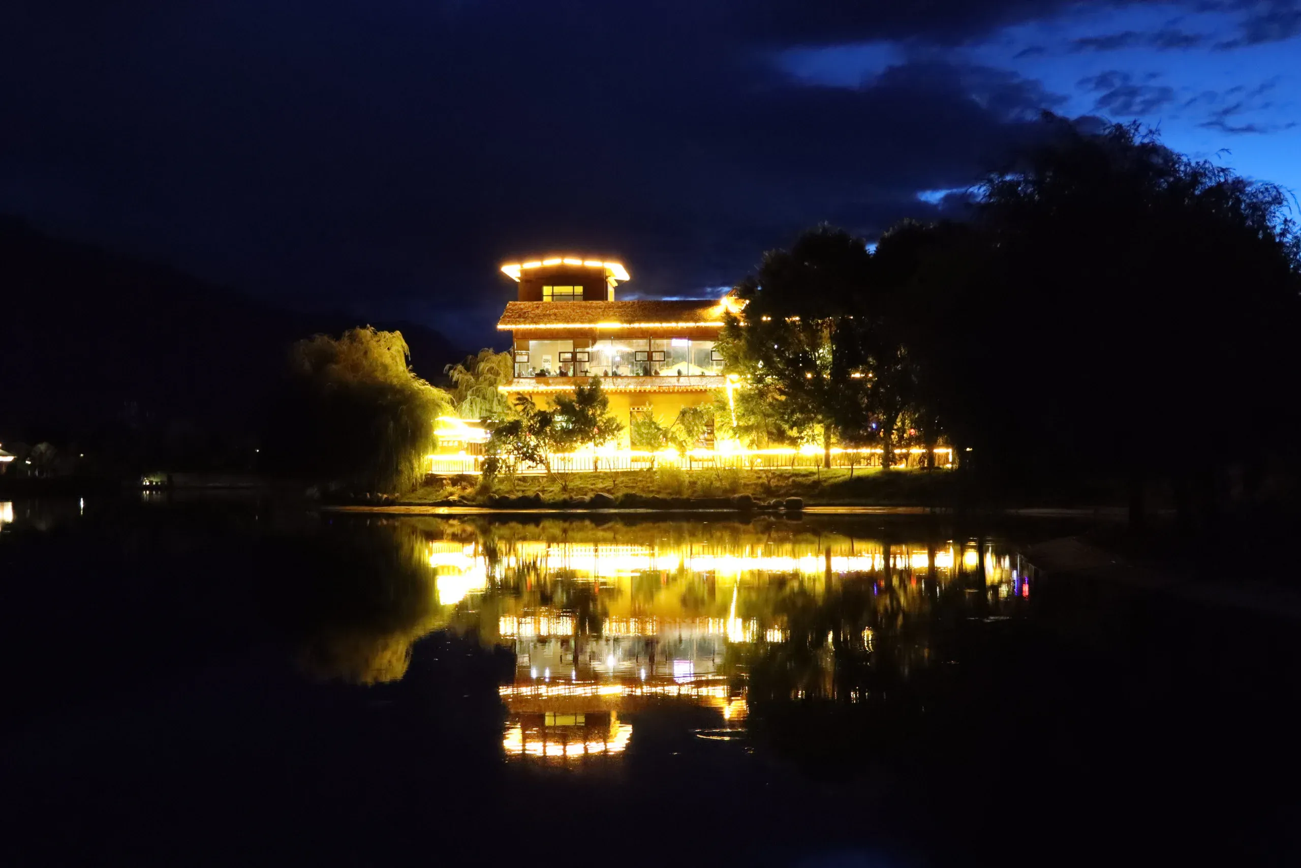 夜色中灯光倒映在水面的藏式建筑